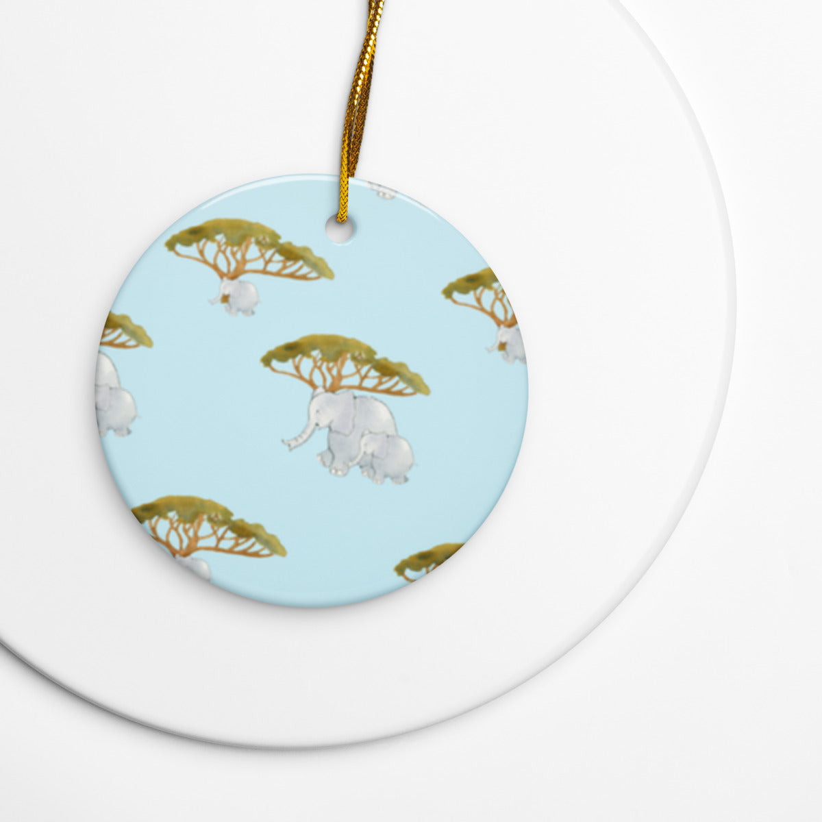 Elephant and Trees ceramic ornament on a gold string over a white plate