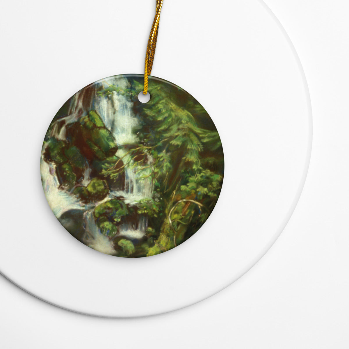 Woodland Waterfall ceramic ornament on a gold string over a white plate