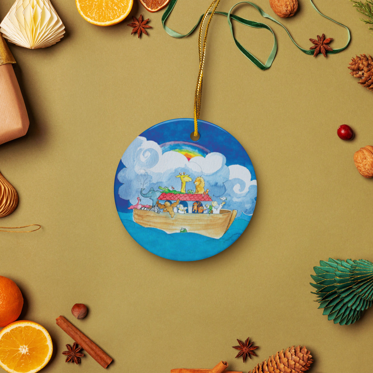 Noah's Ark ceramic ornament on a gold string among holiday oranges and pinecones
