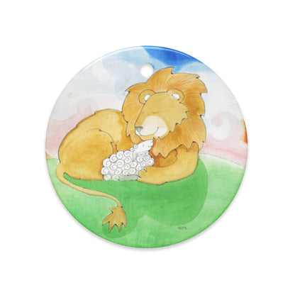 Lion and Lamb ceramic ornament, round, with a golden lion holding a white lamb on a green hill