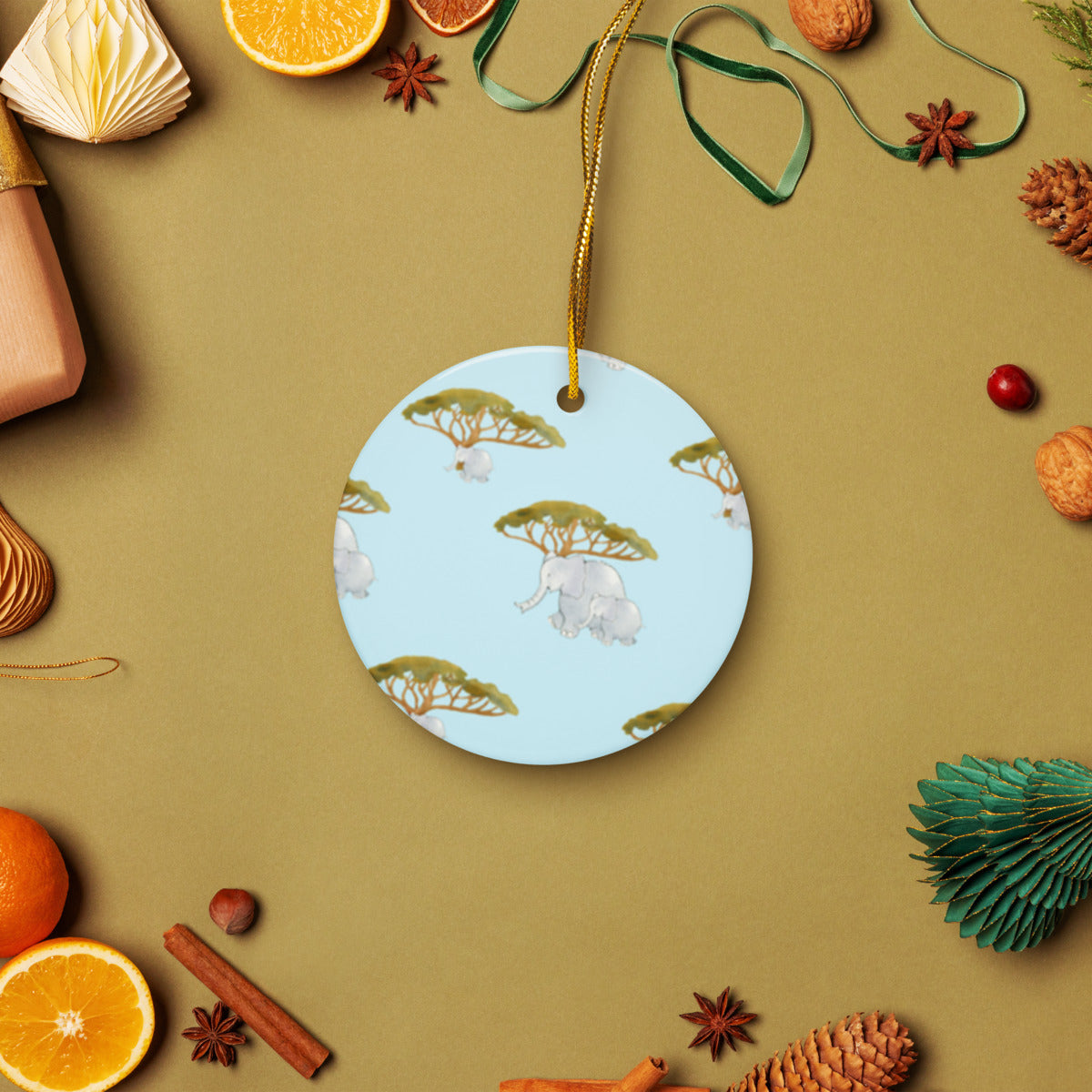 Elephant and Trees ceramic ornament on a gold string among holiday oranges and pinecones