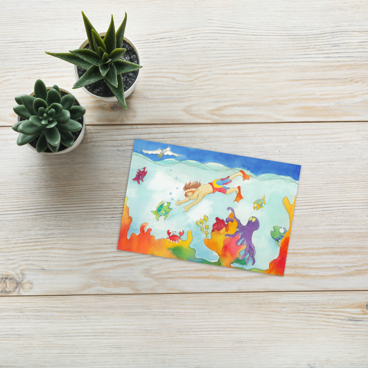 Diver greeting card on a wooden table beside small succulents